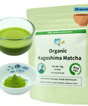 Product photograph displaying Organic Kagoshima Matcha tea in three complementary presentations against a white background. The image is artfully arranged to showcase the complete product experience. On the left side, a clear glass bowl with a green-tinted bottom contains freshly whisked bright green matcha tea with a frothy surface, demonstrating the traditional preparation that creates a smooth, vibrant beverage. Below this, a small white porcelain dish adorned with blue fish designs contains a small mound of fine, vibrant green matcha powder in its dry form, highlighting the tea's rich color and fine texture before brewing. On the right, a light green resealable pouch features the product name 'Organic Kagoshima Matcha' prominently displayed on a white label. The package indicates '20 servings' in a blue label at the top corner, alongside an illustration of a traditional clay tea bowl. Product specifications include 'Net Wt. 40g (1.4oz)' and 'Ceremonial Grade' designation, indicating premium quality. The packaging includes two distinctive circular logos - one featuring what appears to be a geographical landmark representing the Kagoshima region, and another displaying Japanese characters (鹿児島の恵み) within a green brush stroke circle, likely meaning 'Blessings of Kagoshima' or 'Gifts from Kagoshima.' A green banner across the top of the label displays the brand's cartoon shark logo with text 'all day i eat like a shark | tea shop.' Descriptive text highlights the tea's qualities: 'Mineral Rich-Heritage | Bright and Smooth' and 'Saemidori Cultivar | Stone-milled for Superior Flavor,' emphasizing both the regional terroir and traditional processing methods that contribute to this matcha's distinctive character. The organic certification indicates the tea is grown without synthetic pesticides or fertilizers.